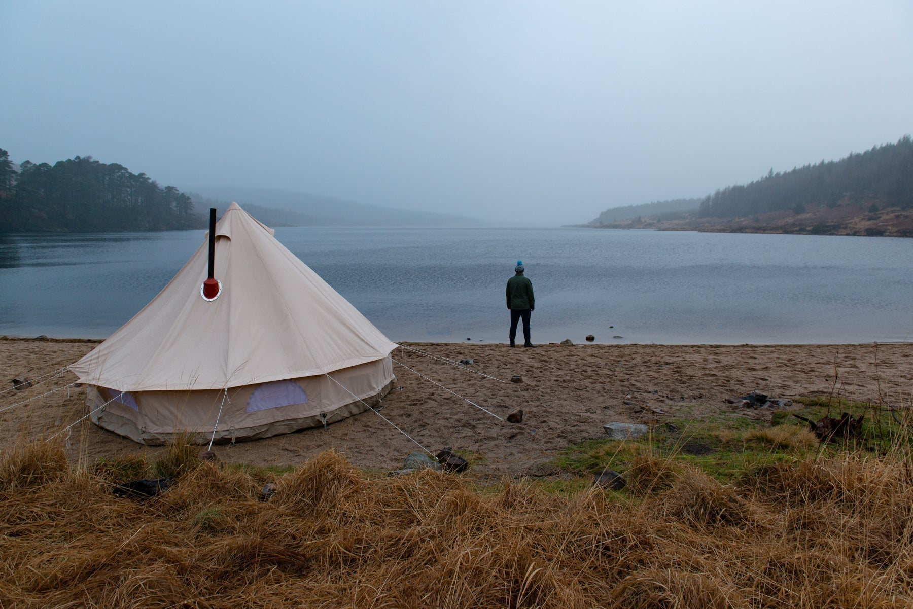 Image of a bell tent pitched by a lake with an Anevay Stoves Flue coming out of the top