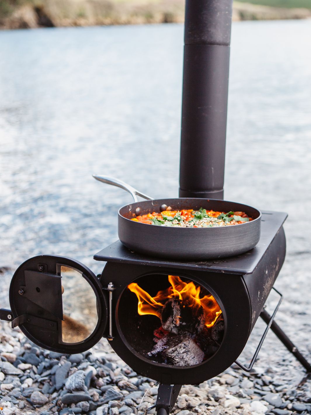 Anevay Frontier Plus set up on a shingle beach with food cooking on top  - Outdoor Wood Burning Stove